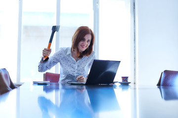 Furious young woman destroying a laptop computer