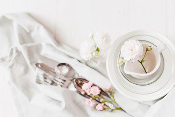 Clean glass and ceramic dishes with roses on a white wooden table. Preparing for breakfast. Soft focus.