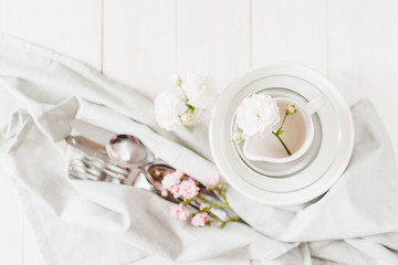 Clean glass and ceramic dishes with roses on a white wooden table. Preparing for breakfast. Soft focus.