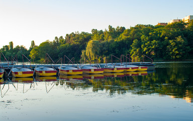 Fototapeta premium Pleasure rowing boats moored at the pier in the evening pond. Donetsk. Ukraine.