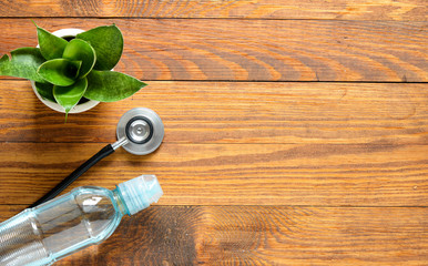 stethoscope, water and flowerpot on wood background