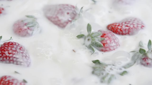 Ripe strawberry falling in milk. Summer berries in white cream