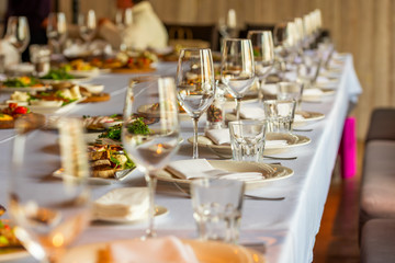 crystal wine glasses on a served banquet table with salads and snacks