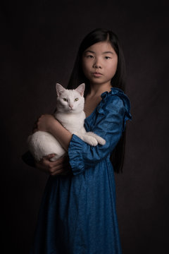 Studio portrait of asian girl in blue dress holding white cat