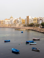 Vertical view of old town Trapani coastline: simple fishermen houses facing the sea, with little rowing blue boats awaiting anchored into the shallow water of the bay. Trapani, Sicily, Italy