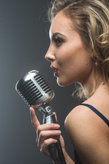 Portreit of sexy young girl singer singing with silver retro microphone