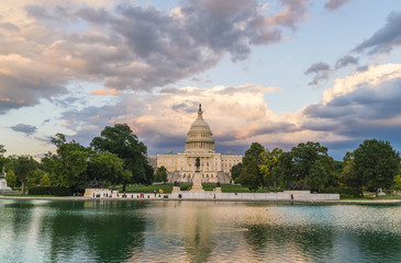 The United States Capitol building at sunset wirh reflection in water.