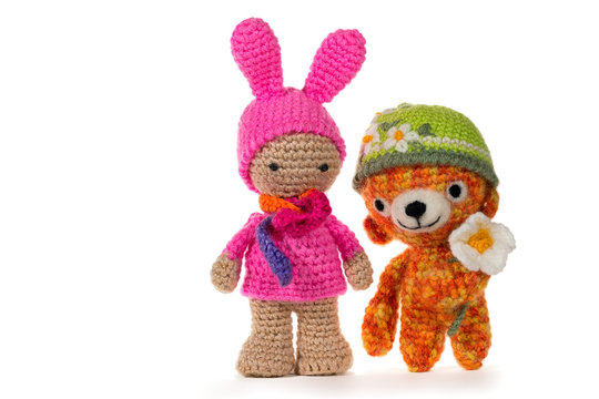 Dressed as a bunny crochet girl and crochet bear wearing a hat with a flower, on white background. Amigurumi. Handmade