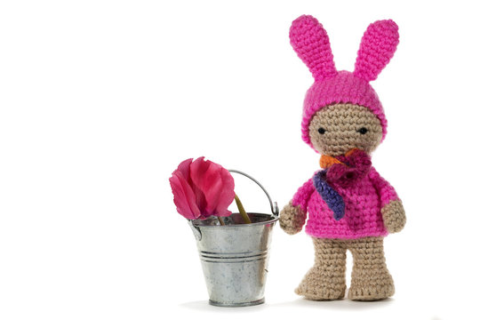 Dressed as a bunny crochet girl and a metal bucket with a flower, on white background. Amigurumi. Handmade