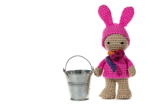 Dressed as a bunny crochet girl and a metal bucket, on white background. Amigurumi. Handmade