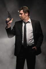 Handsome middle aged detective man with gun on dark background