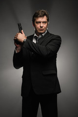 Handsome middle aged detective man with gun on dark background