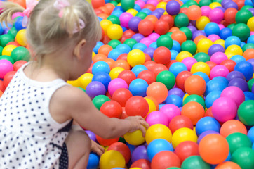 Fototapeta na wymiar A girl in the playroom, where there are a lot of colored balls.
