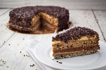 Dark chocolate vegan cake with candies and nuts on wooden background