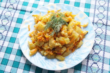 Vegetarian dish of mixed vegetables, Asian and Indian recipe, zucchini, carrots, onions, potatoes, hot and spicy, served in a bowl with a checkered napkin