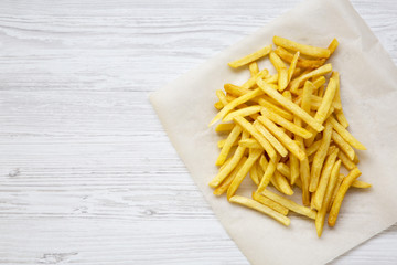 French fries over white wooden background, from above. Copy space.