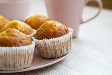 fresh muffins on pink plate over white wooden background, closeup