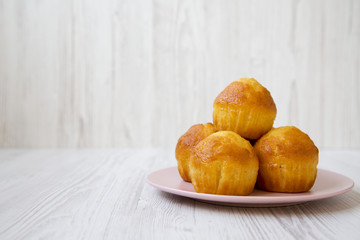Fresh cupcakes on pink plate over white wooden background, side view. Clopy space.