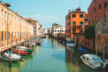Cityscape of Venice with buildings, channel and bridge, sky.