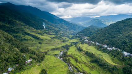 Fototapeta na wymiar Panoramic aerial drone view of beautiful rice terraces surrounded by tall mountains and low cloud