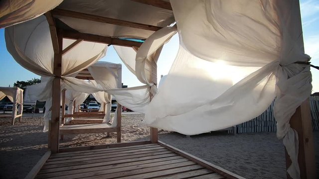 Video of a beach bed with shades, by the sea.