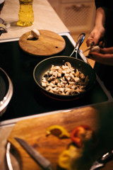 A woman is frying mushrooms and carrots. The cooking process.