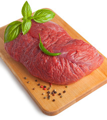 Raw piece of beef with spices on a board, isolated on a white background. Selective focus.