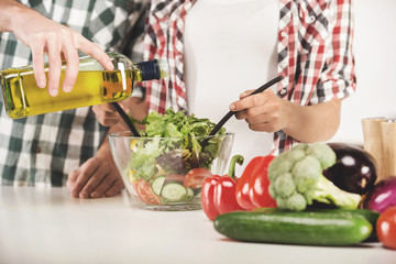 Young couple are preparing salad in kitchen at home.