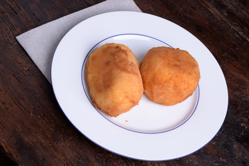 2 Arancine with meat and mozzarella and prociutto on white plate 