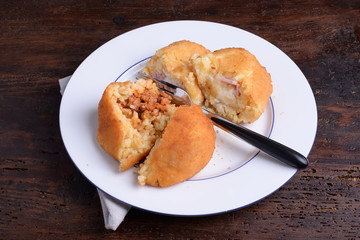 2 Arancine with meat and mozzarella and prociutto on white plate 