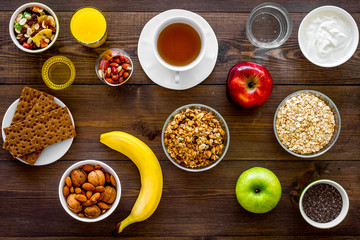 Set of products for healthy vegetarian breakfast. Fruits, oatmeal, yogurt, nuts, crispbreads, chia on dark wooden background top view