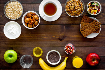 Set of products for healthy vegetarian breakfast. Fruits, oatmeal, yogurt, nuts, crispbreads, chia on dark wooden background top view space for text