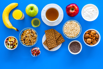 Make a menu for wholesome breakfast. Fruits, oatmeal, yogurt, nuts, crispbreads, chia on blue background top view copy space