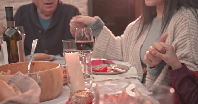 Three-generation family praying at dining table in mediterranean village