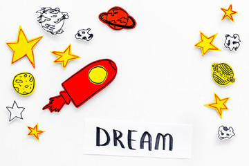 Dream concept. Hand lettering dream at white cosmos background with rocket and stars top view copy space