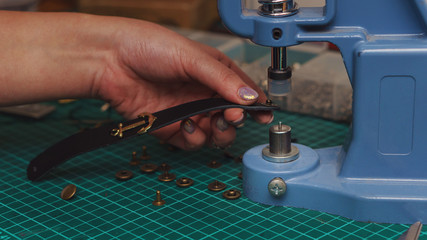 Tanner puts rivets on leather bracelet. Close-up photo. Process of working in workshop.
