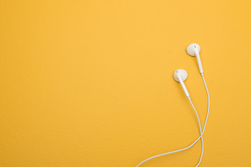 White earphones on yellow background with copy space