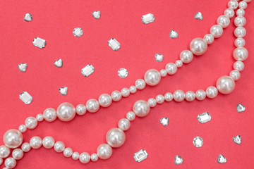 Pearl necklace and shiny gems on pink background