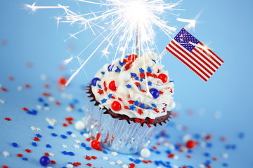 4th of July cupcake with flag, sprinkles, and sparkler