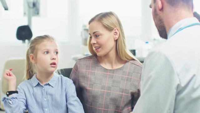 Mother with Sweet Little Girl Visit Friendly Pediatrician. Scared Child Talks about Fear of Needles but Professional Doctor Calms Her Down. Brightand Modern Medical Office.