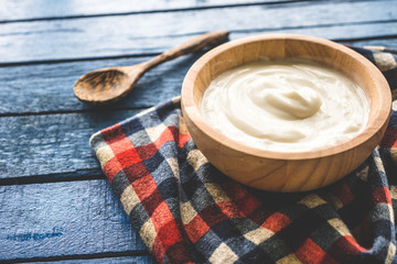 Yogurt in wooden bowl on wooden table