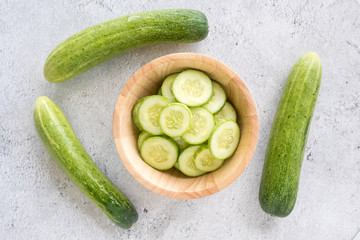 Fresh cucumber slices on a wooden bowl. Top view