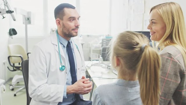 Low Angle Shot of Friendly Doctor Explaining How Medicine Works to a Cute Little Girl and Her Mother. Pediatrician Cures Little Girl. Modern Medical Office. Shot on RED EPIC-W 8K Helium Cinema Camera.