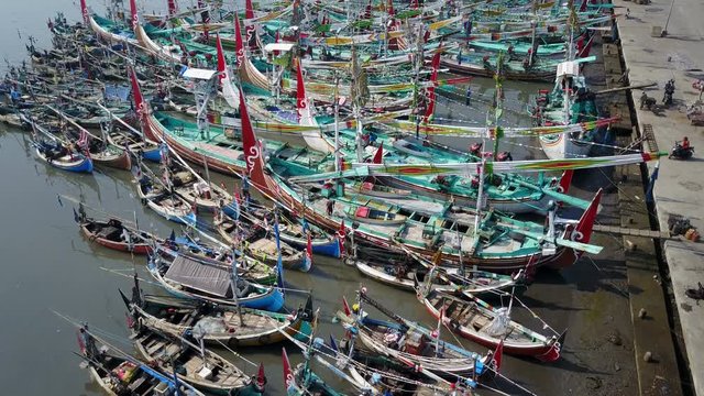 Tilted aerial footage of colorful fishing fleet of traditional vessels in Muncar harbor East Java, Indonesia