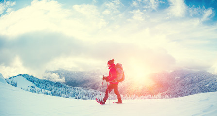 A man in snowshoes in the mountains.