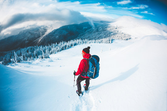 A man in snowshoes in the mountains in the winter.