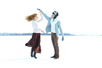 Woman wearing brown skirt and sweater dancing with man in snow background. Concept of wonter photo...