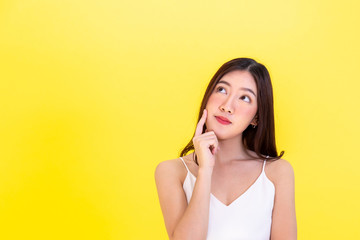 Asian beautiful woman thinking and considering with empty copy space over yellow background