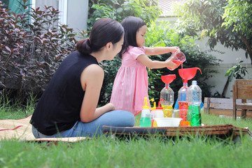 Asian mom and little daughter experiment with different water colors mixing for learning and strengthen Imagine.