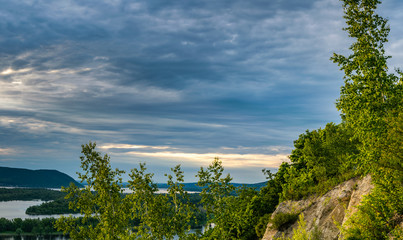 Panoramic landscape with green forest, birch trees, Volga river embankment and hills during sunset in park near Samara city, Russia